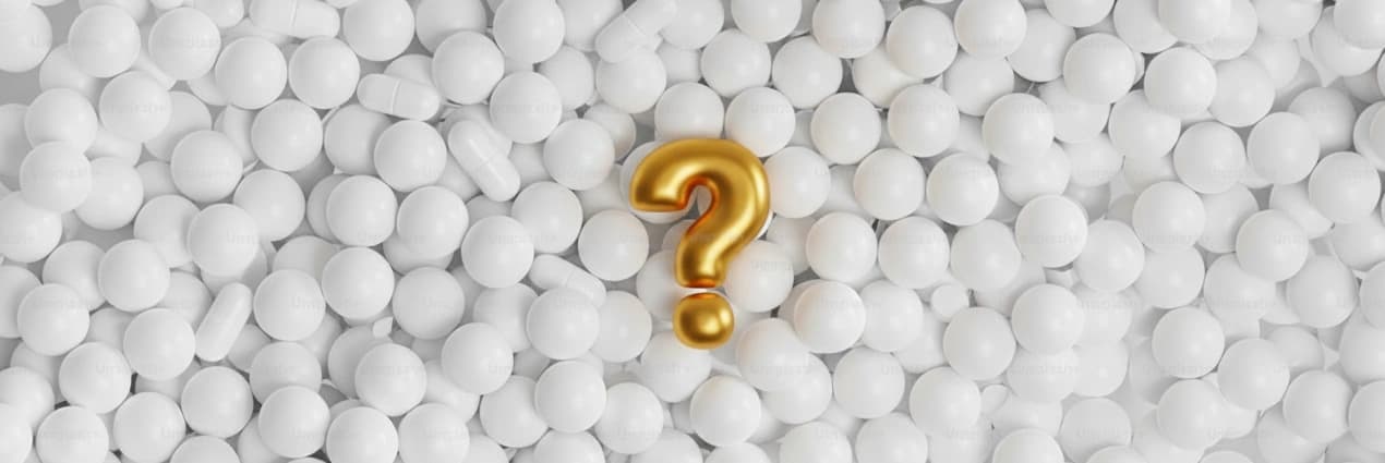 znak zapytania leżący wśród rozsypanych tabletek i pastylek